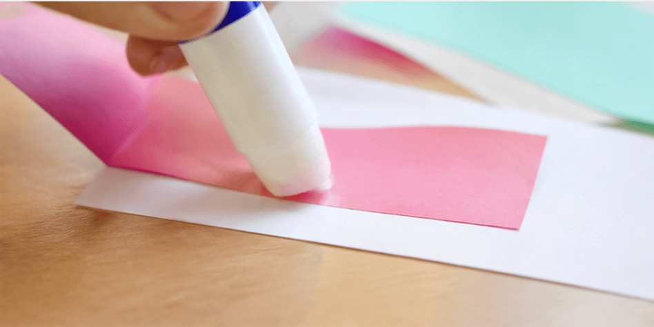 A glue stick pasting colored paper together