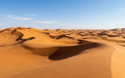 A sandy desert with dunes and a hot sun