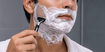 A man shaving with white soap lather on his face